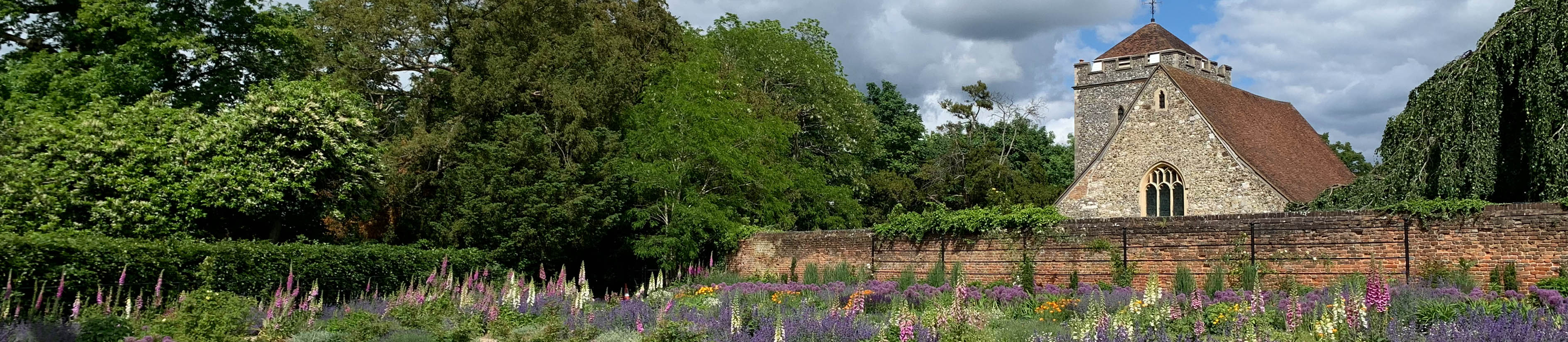 A colourful border of flowers at Stoke Poges Memorial Gardens, with St Giles' Church in the background